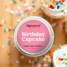 Load image into Gallery viewer, Birthday Cupcake soy candle in a 4 oz travel tin, from the Signature Collection by Angela Rose Studios, shown with colorful sprinkles and frosted cupcakes.